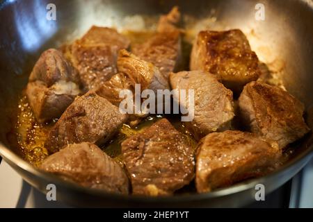 Braciole di maiale (sirloin) che cuocono in una padella d'acciaio inossidabile sulla stufa Foto Stock