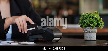 donna d'affari mano premendo il pulsante e strisciare credito sul terminale in piedi nel centro commerciale. shopping e concetto di vendita al dettaglio Foto Stock