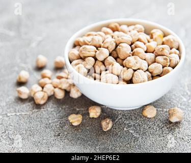 Ceci secchi non cotti in ciotola su fondo grigio di cemento Foto Stock