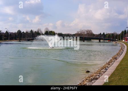 Lago artificiale parzialmente congelato e fontana in un parco cittadino Foto Stock