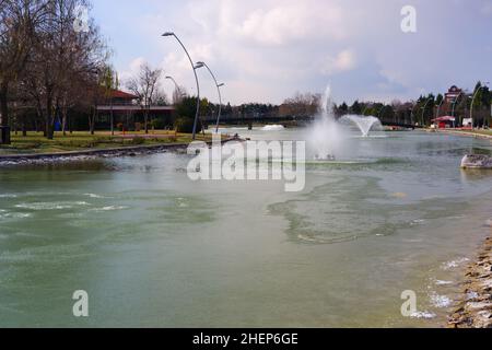 Lago artificiale parzialmente congelato e fontana in un parco cittadino Foto Stock