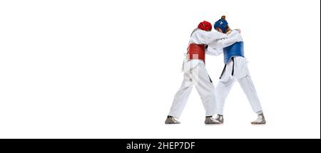 Ritratto di due giovani donne, taekwondo atleti praticando, combattendo isolato su sfondo bianco. Concetto di sport, abilità Foto Stock