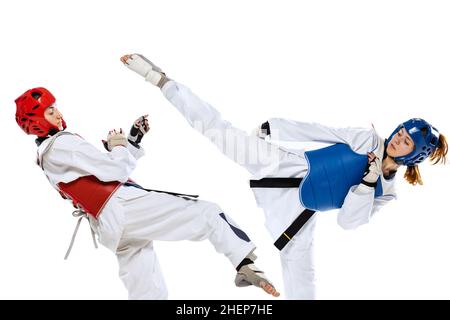 Ritratto di due giovani donne, taekwondo atleti praticando, combattendo isolato su sfondo bianco. Concetto di sport, abilità Foto Stock