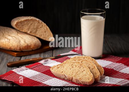 Pane fatto in casa appena sfornato con un bicchiere di latte sul tavolo Foto Stock