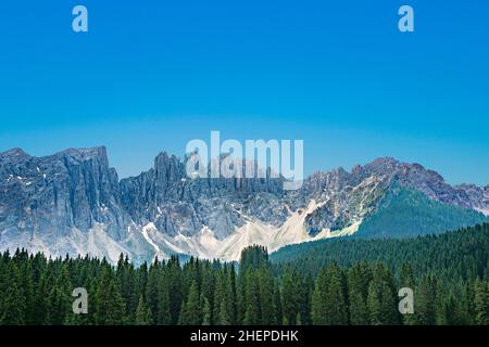 Panorama del Lago di Carezza un lago alpino circondato da un'alta pineta nelle Dolomiti con vista sulla catena montuosa del Rosengarten sullo sfondo in South Tyr Foto Stock