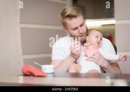 Il padre nutre la figlia naughty che rifiuta di mangiare gli alimenti complementari Foto Stock