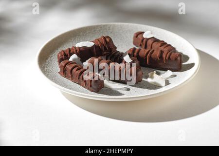 Dolci vegani senza zucchero fatti con noci, datteri e miele. Caramelle vegane fatte in casa da noci, datteri, semi, zucchero senza cacao su un piatto su uno sfondo bianco Foto Stock