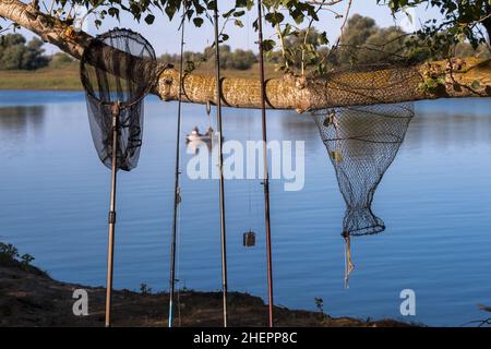 Pesca attrezzi di fondo in una fila sullo sfondo di un grande fiume e pescatori in una barca. Sfondo. Foto Stock