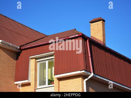 Mansarda tipo di copertura della casa. Esterno del tetto sottotetto con cerniere in asfalto e sistema di gocciolatoio in plastica. Foto Stock