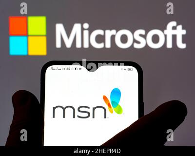 In questa illustrazione della foto, il logo MSN (Microsoft News) viene visualizzato sullo smartphone e sullo sfondo il logo Microsoft. Foto Stock