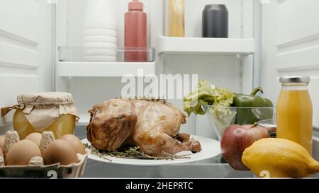tacchino arrosto preparato per cena di ringraziamento vicino a verdure fresche, frutta e contenitori con cibo in frigorifero Foto Stock