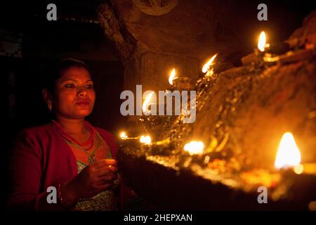 Donna newari locale che fa puja (preghiera/offerta) ad un santuario indù illuminato a candela durante il Capodanno nepalese (Bisket Jatra) festeggiamenti a Bhaktapur. Foto Stock