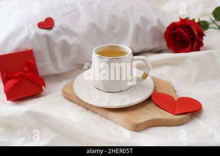 Colazione in camera tazza di tè verde, scatola regalo con cuori e rose. Colazione di San Valentino a letto, Festa della mamma o Festa della donna Foto Stock