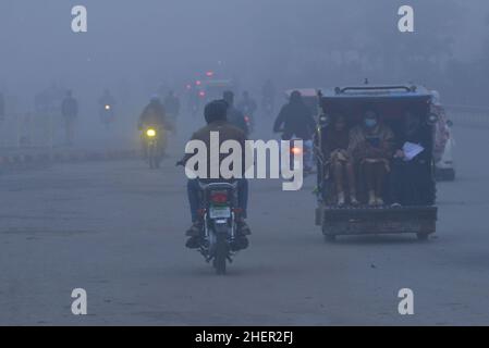 Cittadini pakistani, studenti in viaggio durante una fredda e densa mattinata di smog a Lahore, Pakistan, il 11 gennaio 2022. I residenti e i pendolari pakistani sono più preoccupati che sorpresi a causa dello strato improvviso di smog denso che sta causando problemi di respirazione, visibilità e ha anche ostacolato il flusso regolare del traffico che ha ridotto la visibilità per i pendolari e ha provocato diverse lamentele di problemi respiratori e angoscia mentale. (Foto di Rana Sajid Hussain / Pacific Press/Sipa USA) Foto Stock