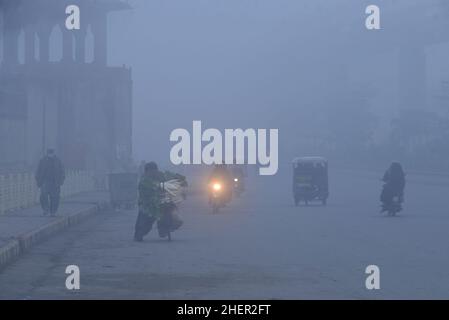 Cittadini pakistani, studenti in viaggio durante una fredda e densa mattinata di smog a Lahore, Pakistan, il 11 gennaio 2022. I residenti e i pendolari pakistani sono più preoccupati che sorpresi a causa dello strato improvviso di smog denso che sta causando problemi di respirazione, visibilità e ha anche ostacolato il flusso regolare del traffico che ha ridotto la visibilità per i pendolari e ha provocato diverse lamentele di problemi respiratori e angoscia mentale. (Foto di Rana Sajid Hussain / Pacific Press/Sipa USA) Foto Stock