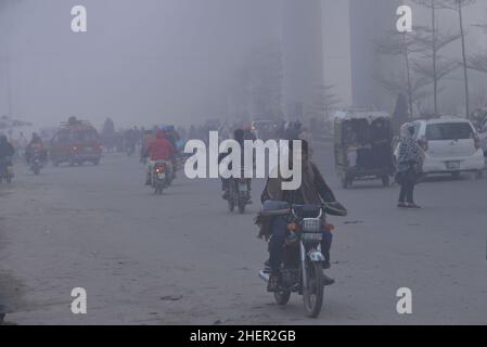 Cittadini pakistani, studenti in viaggio durante una fredda e densa mattinata di smog a Lahore, Pakistan, il 11 gennaio 2022. I residenti e i pendolari pakistani sono più preoccupati che sorpresi a causa dello strato improvviso di smog denso che sta causando problemi di respirazione, visibilità e ha anche ostacolato il flusso regolare del traffico che ha ridotto la visibilità per i pendolari e ha provocato diverse lamentele di problemi respiratori e angoscia mentale. (Foto di Rana Sajid Hussain / Pacific Press/Sipa USA) Foto Stock