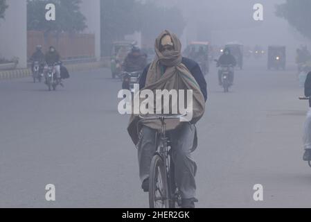 Cittadini pakistani, studenti in viaggio durante una fredda e densa mattinata di smog a Lahore, Pakistan, il 11 gennaio 2022. I residenti e i pendolari pakistani sono più preoccupati che sorpresi a causa dello strato improvviso di smog denso che sta causando problemi di respirazione, visibilità e ha anche ostacolato il flusso regolare del traffico che ha ridotto la visibilità per i pendolari e ha provocato diverse lamentele di problemi respiratori e angoscia mentale. (Foto di Rana Sajid Hussain / Pacific Press/Sipa USA) Foto Stock