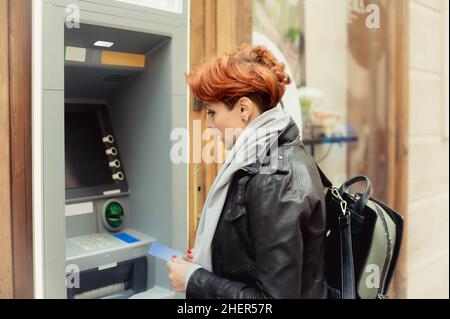 Donna d'affari che ritira denaro dalla carta di credito al bancomat Foto Stock