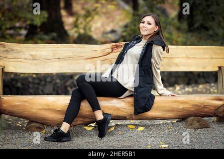 Ritratto di una bella giovane tatar felice in piena crescita seduta su una panca di legno in un parco all'aperto. Foto di alta qualità Foto Stock