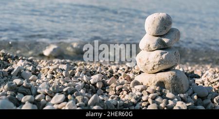 Mucchio di pietre di ciottoli sul mare blu sullo sfondo. Primo piano Foto Stock