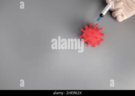 Mano in guanto bianco che tiene la siringa su sfondo grigio con spazio di copia. Dà iniezione in virus, batteri trattamento medico concetto. Vaccinazione Foto Stock