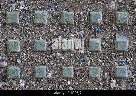 Primo piano di alcuni piccoli ciottoli quadrati trovati sotto un ponte a doppia carreggiata, formando un modello simmetrico tre per cinque Foto Stock