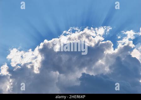 Raggi solari che irradiano attraverso la parte superiore di una grande nuvola di cumuli Foto Stock