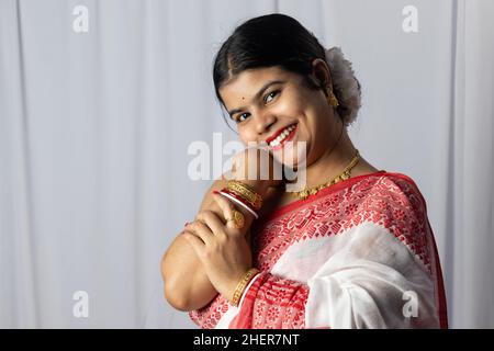 Una donna indiana in rosso saree con sanghetta con faccia sorridente su sfondo bianco Foto Stock