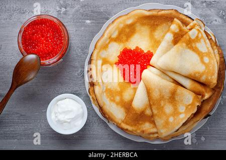 Impila di sottili pancake frullati con caviale rosso e panna acida fresca Foto Stock