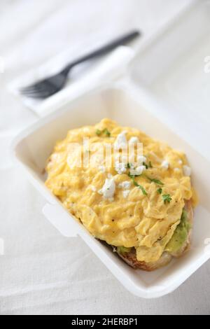 Avocado e toast con uova strapazzate con consegna a domicilio su sfondo bianco Foto Stock