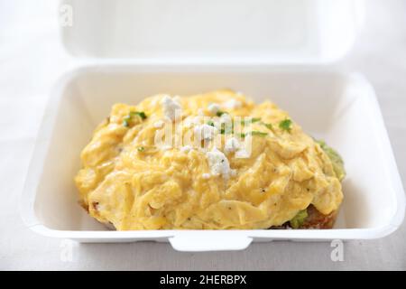 Avocado e toast con uova strapazzate con consegna a domicilio su sfondo bianco Foto Stock