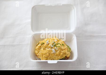 Avocado e toast con uova strapazzate con consegna a domicilio su sfondo bianco Foto Stock