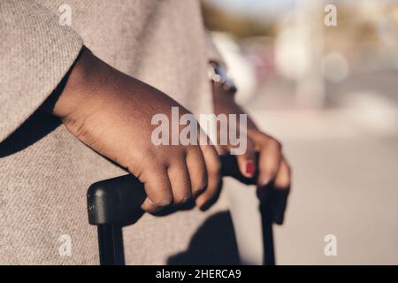 dettaglio delle mani di una donna d'affari nella valigia in attesa di un veicolo sulla strada Foto Stock