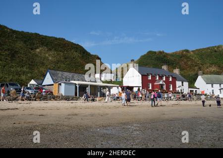 I turisti si riuniscono di fronte al Ty Coch Inn sulla spiaggia nel villaggio di Porth Dulllaen, Galles del Nord Foto Stock