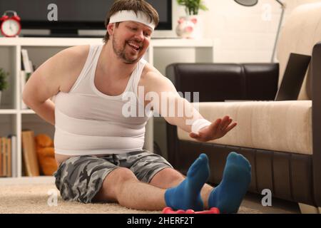 L'uomo di idoneità si trova su tappeto spesso con peso in eccesso, esegue esercizi di stretching Foto Stock