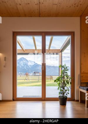 Vista della montagna attraverso la porta nel giardino con tetto in vetro di legno terrazza Foto Stock
