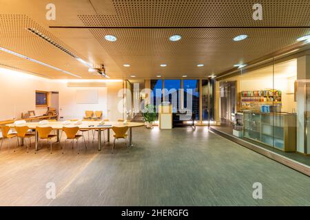 grande sala riunioni in un edificio di uffici in legno con soffitto acustico e pareti divisorie scorrevoli in vetro Foto Stock