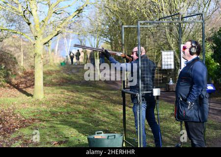 Due uomini tiro al piccione di argilla, uno che prende la mira mentre l'altro sta rilasciando le argille Foto Stock