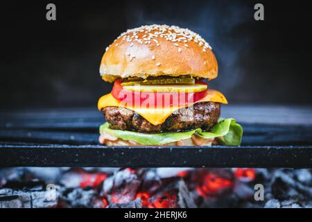 Burger classico e succosa preparato su una griglia barbecue a carbone. Fast food Foto Stock