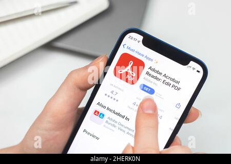 Kharkov, Ucraina - 10 gennaio 2022: Primo piano dell'icona di Adobe Acrobat Reader. La donna utilizza l'applicazione Foto Stock