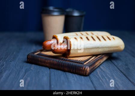 hot dog francese in un rotolo con salsa di ketchup con una bevanda a base di caffè in un bicchiere Foto Stock