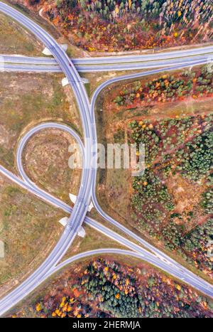 Vista aerea su una strada circolare intersezione vicino alla splendida foresta autunno. Paesaggio con strada rurale vuota, alberi con foglie rosse e arancioni. Autostrada t Foto Stock