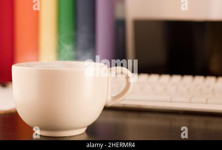 tazza di tè bianco con vapore caldo sulla scrivania. Foto Stock