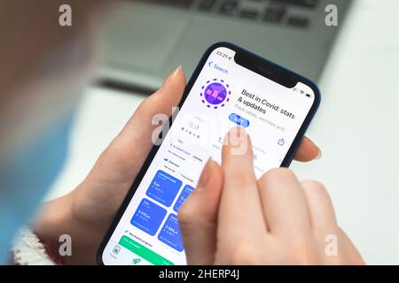 Kharkov, Ucraina - 10 gennaio 2022: COVID-19 Stats app primo piano. La donna utilizza l'applicazione su Apple iPhone 12 Foto Stock