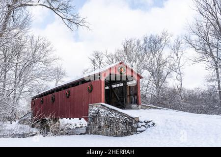 Storico Pool Forge Covered Bridge con neve in una luminosa giornata invernale nella contea di Lancaster, Pennsylvania, USA Foto Stock