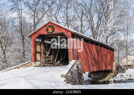 Storico Pool Forge Covered Bridge con neve in una luminosa giornata invernale nella contea di Lancaster, Pennsylvania, USA Foto Stock