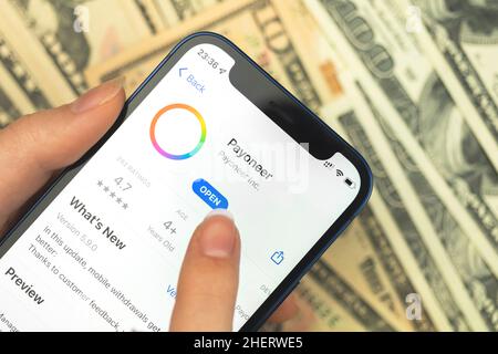 Kharkov, Ucraina - 10 gennaio 2022: Primo piano dell'icona di Payoneer app. Donna con applicazione su Apple iPhone 12 Foto Stock