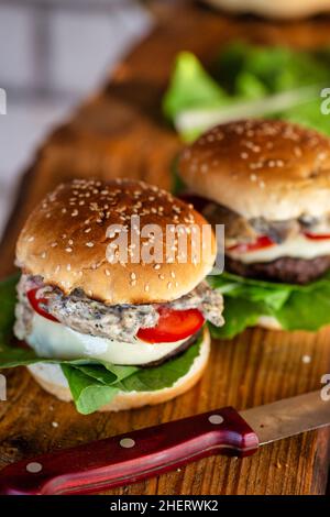 Gustosi hamburger freschi alla griglia su sfondo rustico. Cheeseburger fatto in casa. Foto Stock