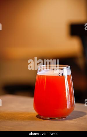 Birra artigianale color ambra rossa acidita in un bicchiere sulla superficie di legno, ricca schiuma frizzante con spazio per la copia Foto Stock