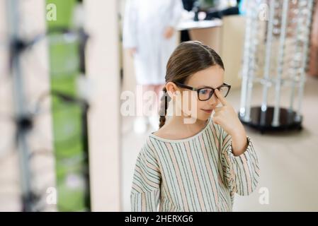 sorridendo bambino che prova sugli occhiali in negozio di ottica su primo piano sfocato Foto Stock
